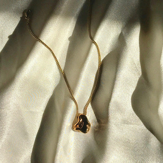 Elegant gold necklace on top of white satin sheet of cloth.