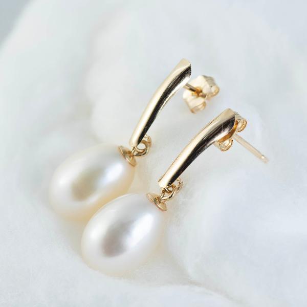 Close-up of NY Gold & Silver Trading Inc.'s 14K Yellow Gold Freshwater Pearl Drop Earrings, part of the exquisite Goddess Jewelry collection, resting on a soft white surface. The earrings feature a sleek gold bar design, enhancing their sophisticated appearance.