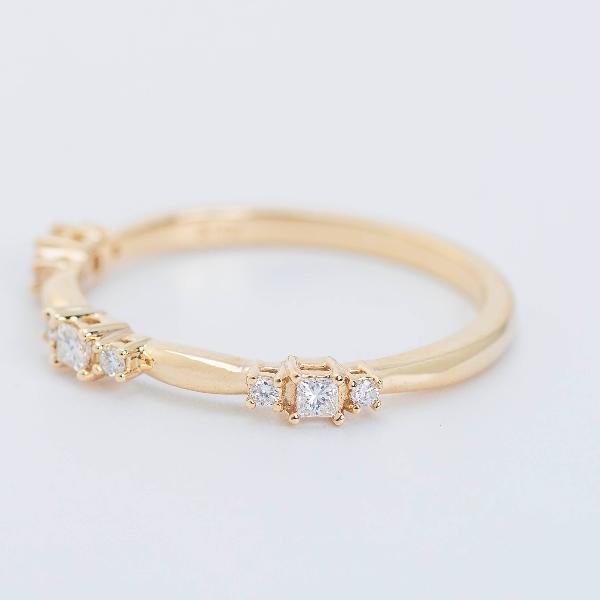 The "14K Yellow 1/6 CTW Natural Diamond Stackable Ring" from Goddess Jewelry is a delicate gold ring showcasing small square-cut diamonds along the band, elegantly displayed against a plain white background.
