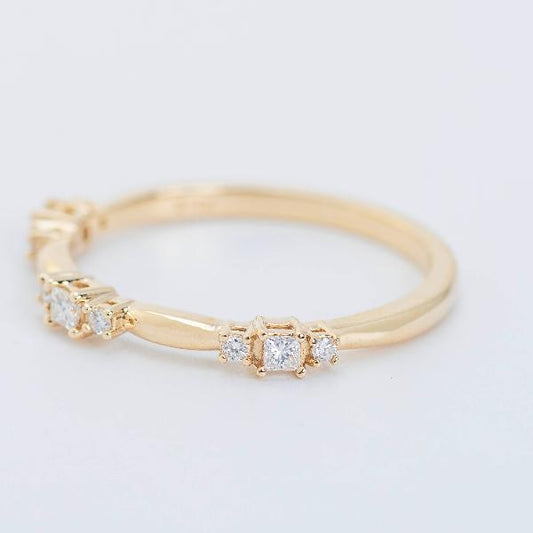 The "14K Yellow 1/6 CTW Natural Diamond Stackable Ring" from Goddess Jewelry is a delicate gold ring showcasing small square-cut diamonds along the band, elegantly displayed against a plain white background.