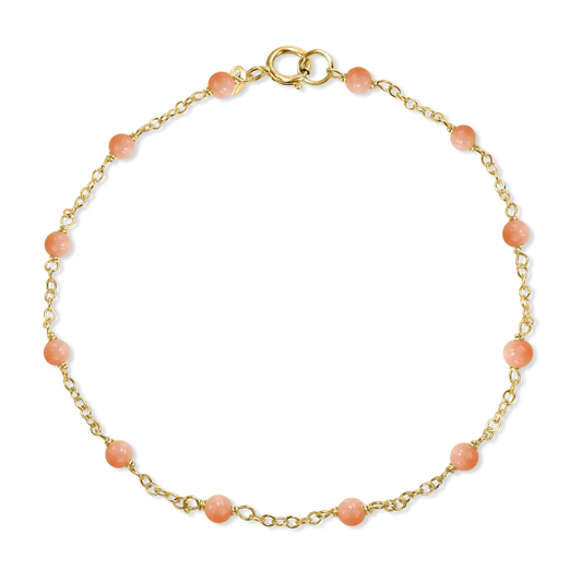 The 14k Pink Coral Station Bracelet from the Goddess Jewelry Collection is a delicate gold chain bracelet adorned with evenly spaced pink beads and a circular clasp, offering a subtle touch of color in its simple, elegant design.