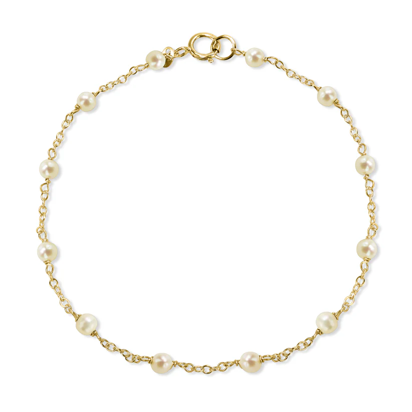 The 14k White Pearl Station Bracelet from the Goddess Jewelry Collection is a delicate gold chain bracelet featuring evenly spaced white pearls connected by thin gold links, with a small gold clasp. Its elegant and simple design is ideal for those seeking refined jewelry.