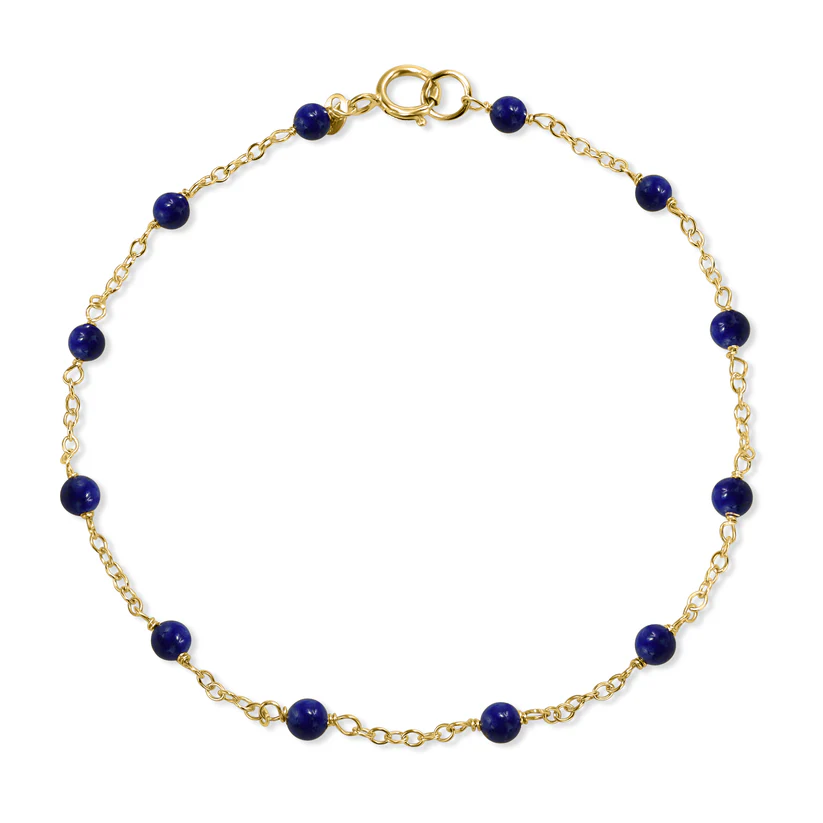 The 14k Lapis Station Bracelet  from the Goddess Jewelry Collection is a delicate gold bracelet with small round dark blue beads evenly spaced along the chain and a gold clasp for fastening.