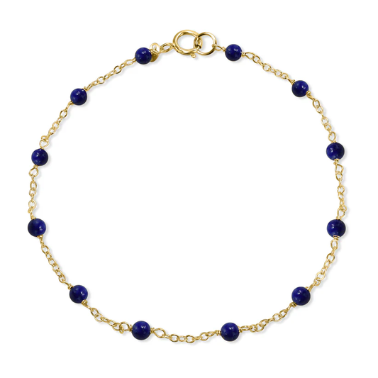 The 14k Lapis Station Bracelet  from the Goddess Jewelry Collection is a delicate gold bracelet with small round dark blue beads evenly spaced along the chain and a gold clasp for fastening.
