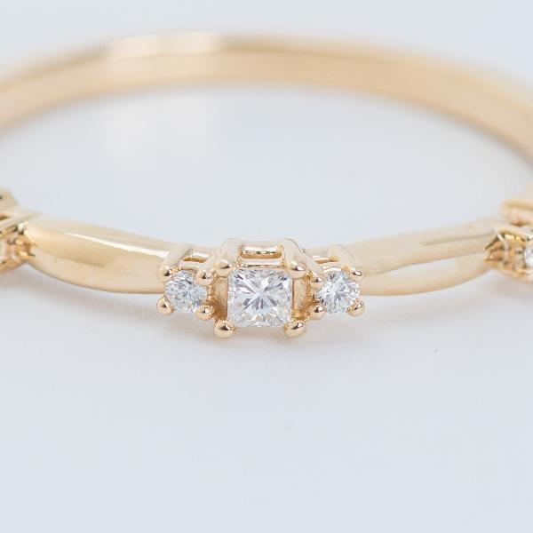 The 14K Yellow 1/6 CTW Natural Diamond Stackable Ring from Goddess Jewelry features a central square-cut diamond flanked by two smaller round-cut diamonds, all elegantly displayed against a soft white background.