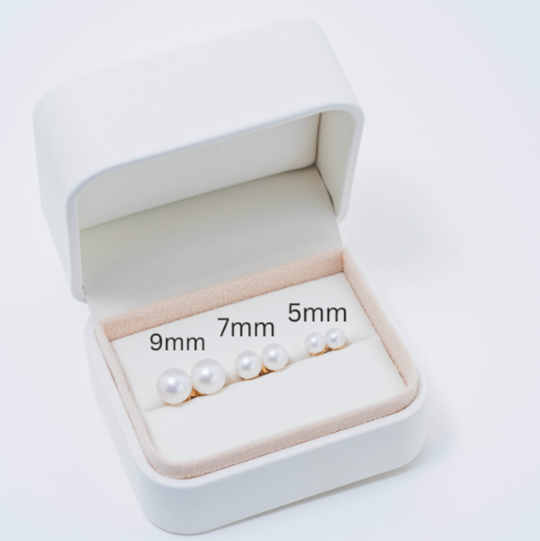 A white jewelry box from Jewelmak opens to reveal five exquisite pearls, 5mm to 9mm from right to left, elegantly displayed on a soft light beige interior.