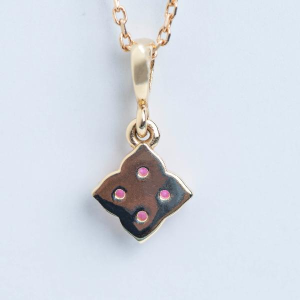 The Stuller Youth 14K Lab-Grown Pink Sapphire Necklace showcases a quatrefoil pendant with four lab-grown pink sapphires at the center, elegantly displayed on a delicate gold chain against a light background.