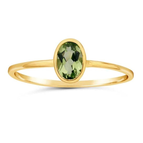 The Rio Grande 14K Yellow Gold Oval Peridot Ring (Size 7) features an AAA-Grade faceted oval peridot at the center. Its thin band and sparkling design make it a perfect stackable ring, elegantly showcased on a white background.