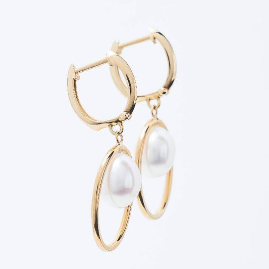 14k Freshwater White Pearl Huggie Hoop Earrings  feature hanging pearls in oval gold frames, set against a plain white background.