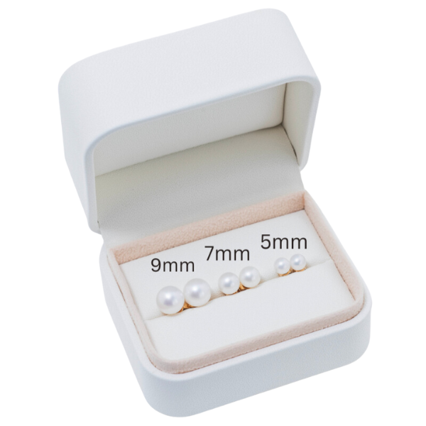 A white jewelry box from Goddess Jewelry reveals three pairs of 14k yellow gold AAA+ quality pearl stud earrings. The 14k white freshwater pearls are arranged from right to left, increasing in size at 5mm, 7mm, and 9mm. This is the "14k White Freshwater Pearl Stud Earrings Gift Set.