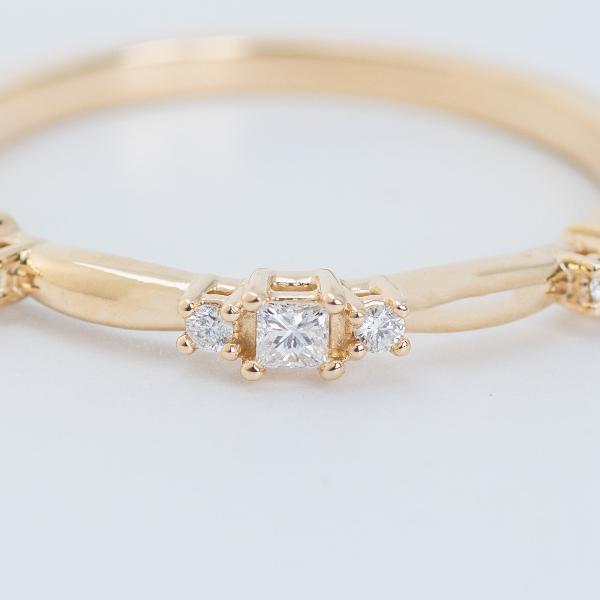 A close-up of Stuller's 14K Yellow 1/6 CTW Natural Diamond Stackable Ring showcases a central square-cut natural diamond flanked by two smaller round diamonds, all set on a smooth, elegant band design that's perfect for versatile wear.