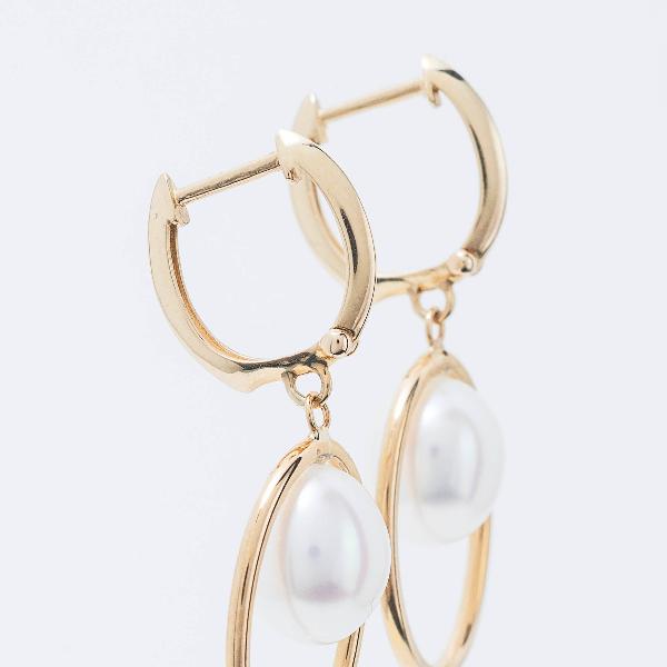 14k Halo White Freshwater Pearl Huggie Hoop Drop Earrings feature a sleek and elegant design with luminous oval pearls gracefully dangling from each hoop, set against a plain background.