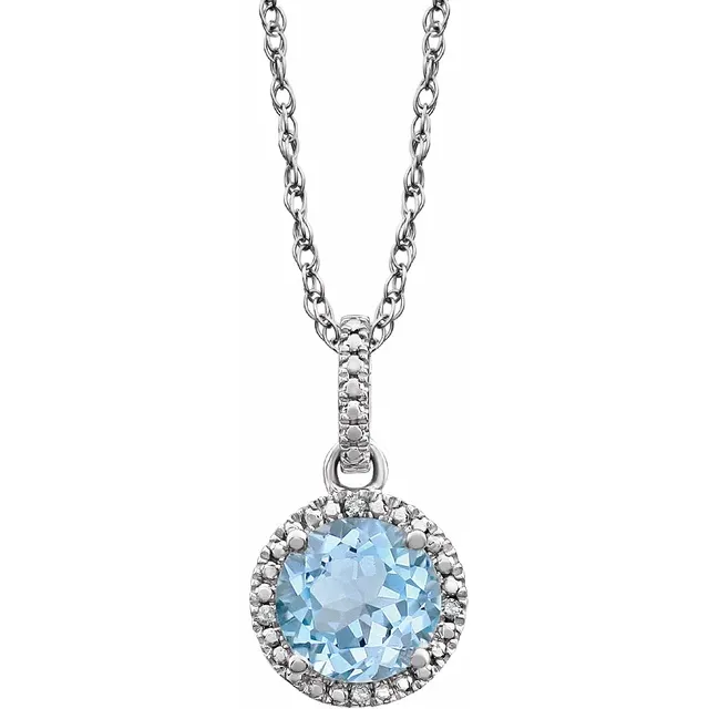 The Stuller Sterling Silver Natural Sky Blue Topaz Round Necklace features a round pendant with a large topaz surrounded by small clear stones. The delicate chain includes diamond accents, enhancing the pendant's elegant design.